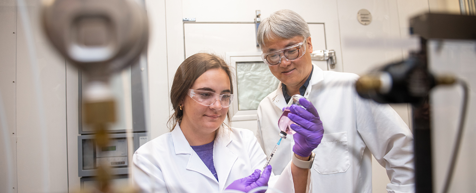 Faculty member instructs a student in a lab.