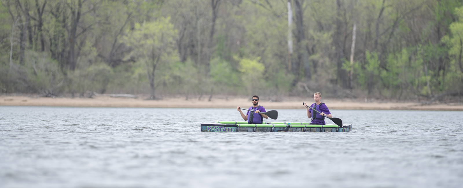 Two students paddle the concrete canoe across water.